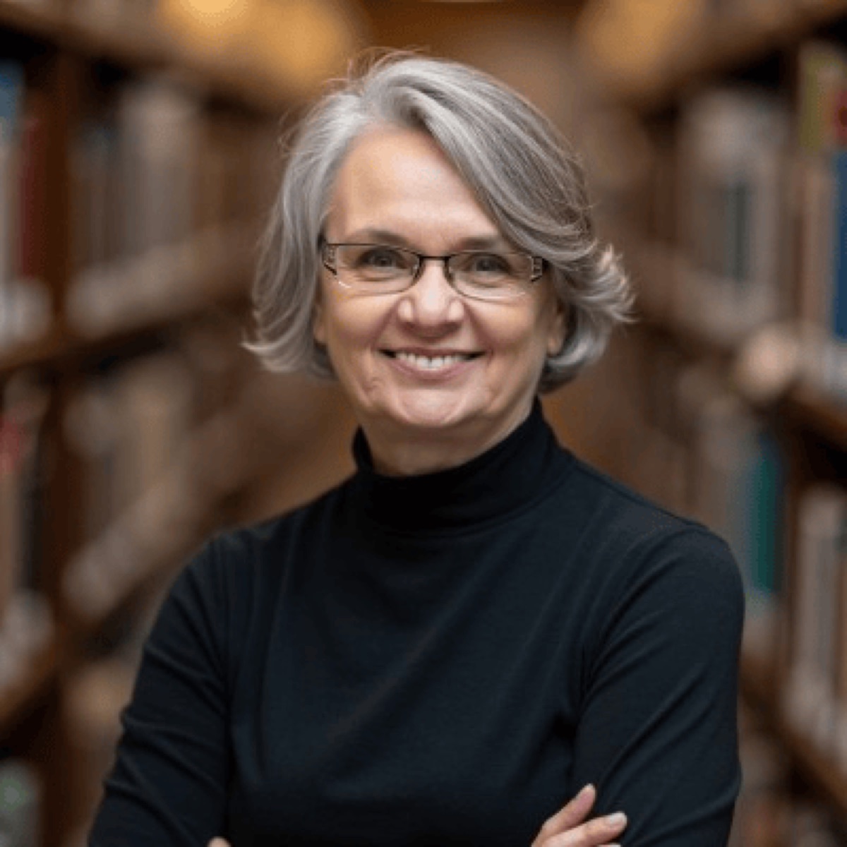 Tammie Nielsen in a black top, smiling in front of bookshelves