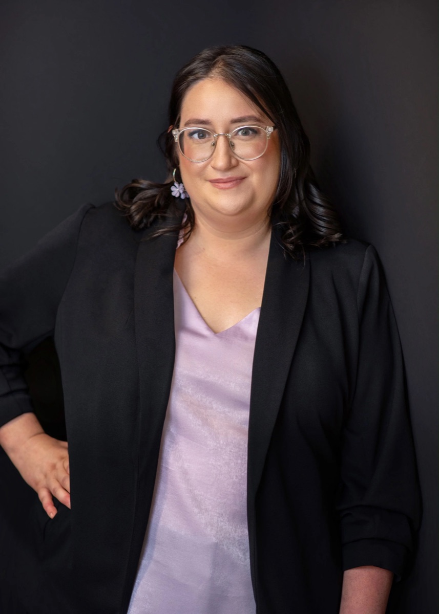 Tiffany Perkinz in glasses, a black blazer, and a lavender blouse